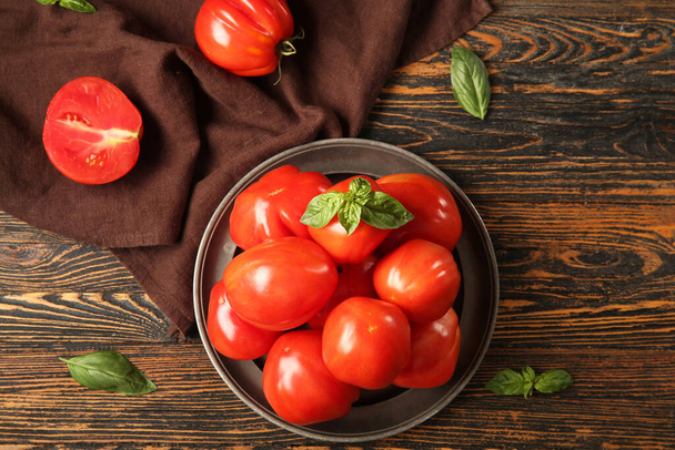Assiette avec tomates fraîches mûres et basilic sur fond en bois - Photo, image