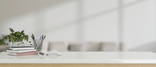 Una mesa blanca con libros, lápices en un soporte de lápiz, una planta en maceta y un espacio de maqueta vacío para mostrar su producto contra una sala de estar blanca moderna borrosa. 3d render, ilustración 3d - Foto, imagen