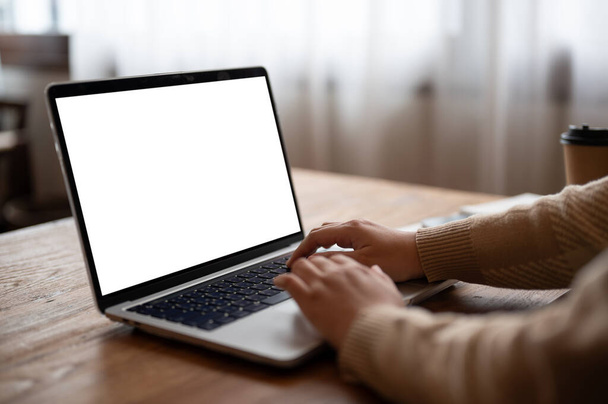 Bilgisayarını kullanan, klavyeye yazı yazan, minimalist bir kafede çalışan bir kadının yakın plan görüntüsü. Laptop beyaz ekran modeli - Fotoğraf, Görsel
