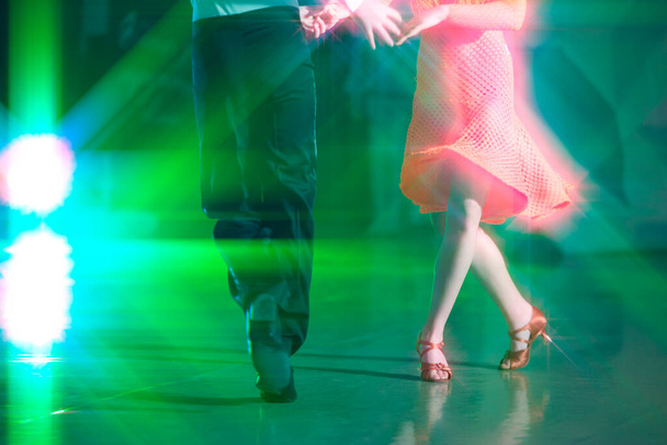 舞台照明の光の中で踊るボールルームの抽象的な背景. ダンサーの足がダンスの動きを作る. - 写真・画像