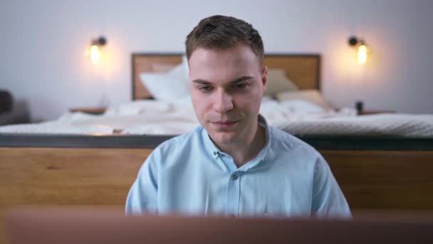 Front view portrait of young smart man talking in slow motion looking at laptop screen. Concentrated confident Caucasian freelancer messaging online from home office - Video