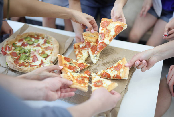 Дорослі та діти беруть шматочок піци на коробці. Концепція доставки фаст-фудів
 - Фото, зображення
