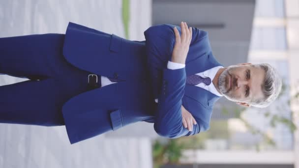 Vertical Video. Handsome Bearded Mature Manager Smiling on Camera while Standing Outdoors, Crossing Hands. Portrait of Positive Office Worker Dressed in Stylish Formal Clothes Outside - Footage, Video