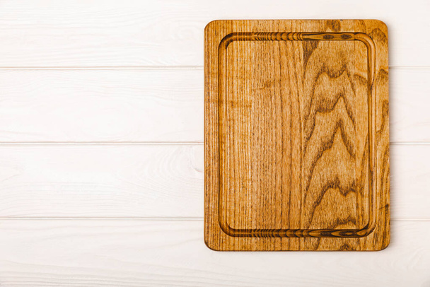 Wooden cutting board on a textured kitchen table. Wooden kitchen board and kitchen towel. Design.MOCKUP. Kitchenware. Place for text. Copy space. Recipe. Cooking concept. - Photo, Image