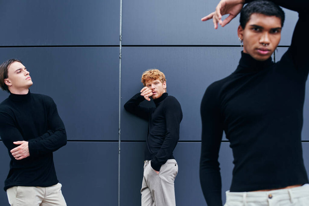 gut aussehende interrassische Gruppe von Männern posiert neben der Wand in lässigen schwarzen Rollkragenpullovern, Mode - Foto, Bild