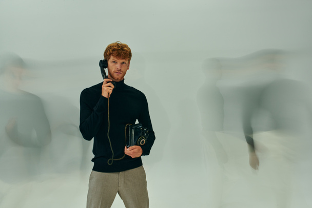 long blurred exposure photo of young man with retro phone surrounded by other male models, men power - Photo, Image