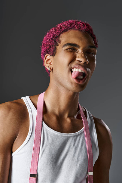 Porträt eines verspielten jungen Mannes, der vor der Kamera die Zunge herausstreckt, Mode und Stil - Foto, Bild