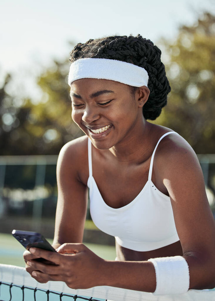 Tenis, sonrisa de mujer negra y texto de teléfono al aire libre para el deporte, fitness y entrenamiento con las redes sociales en la red. Ejercicio, entrenamiento de partidos y redes móviles con sitio web y aplicación en la cancha para el bienestar. - Foto, imagen