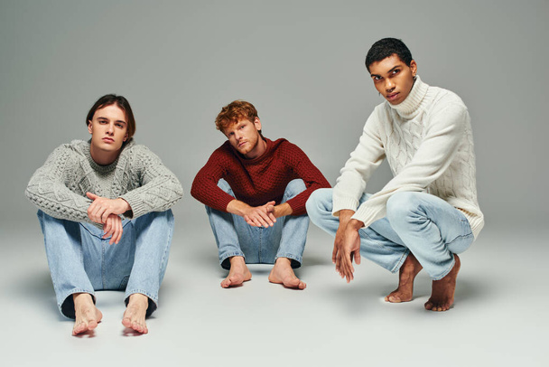 good looking interracial men in casual outfits posing on floor and looking at camera, fashion - Photo, Image