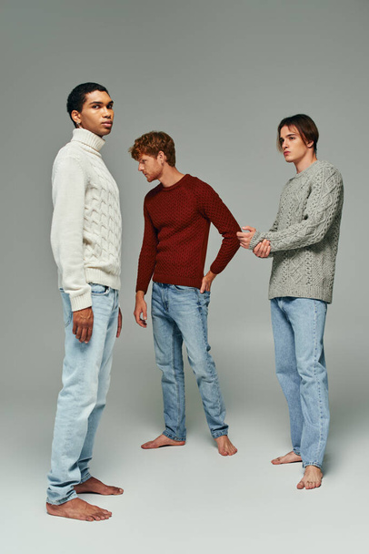 appealing young men in casual attire standing still and posing on gray backdrop, fashion concept - Photo, Image