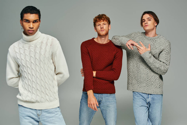 giovane trio multietnico indossa maglioni casual e jeans in posa e guardando la fotocamera, il potere degli uomini - Foto, immagini