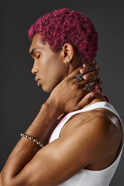 portret młodego mężczyzny w różowych szelkach, z profilem na szarym tle, moda i styl - Zdjęcie, obraz
