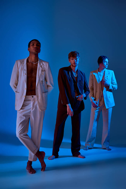 vertikale Aufnahme eleganter Männer in edlen Anzügen, die mit Neonlicht im Gesicht stehen und posieren - Foto, Bild