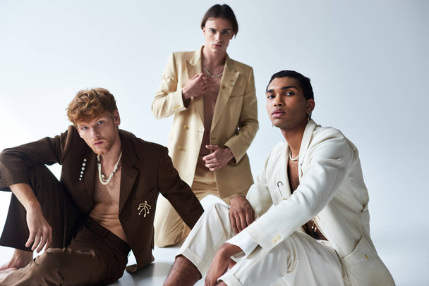 Üç tane zarif takım elbiseli genç erkek model kameraya bakıyor, erkeklerin gücü... - Fotoğraf, Görsel