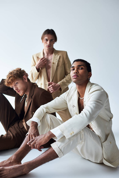 όμορφοι και ποικίλοι άνδρες με κομψά κοστούμια με αξεσουάρ που ποζάρουν στο πάτωμα, έννοια της μόδας - Φωτογραφία, εικόνα