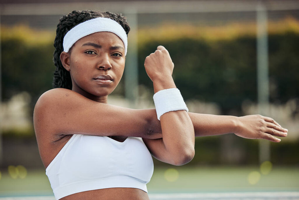 Sports, portrait and woman tennis player doing warm up for practice to play match at stadium. Fitness, serious and African female athlete with stretching exercise for training on court for tournament. - Photo, Image