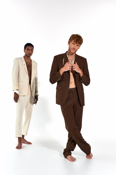 handsome interracial friends posing barefoot in elegant suits with accessories, looking at camera - Foto, Bild