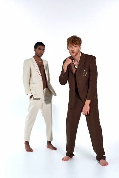 mooie elegante diverse mannen in pakken poseren levendig op witte achtergrond, op zoek naar camera, mode - Foto, afbeelding