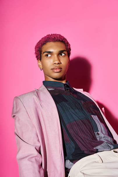 hombre guapo con el pelo rizado rosa posando sobre el telón de fondo rosa y mirando hacia otro lado sobre el telón de fondo rosa - Foto, imagen