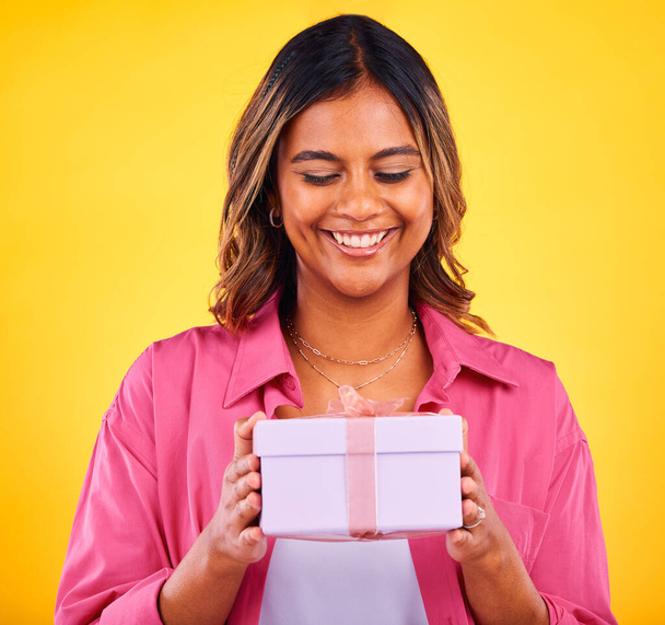 Glückliche Frau, Geschenkbox und Geschenk zum Geburtstag, Ereignis oder Sieg vor gelbem Studiohintergrund. Weibliche Person lächelt mit Preis, Geschenk oder Feier für Überraschung, Paket oder Schleifenpaket. - Foto, Bild