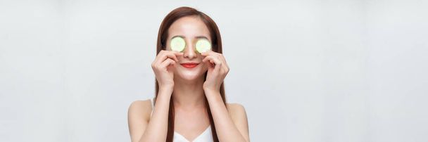 spandoek van aziatische vrouw met komkommer plakjes op haar ogen  - Foto, afbeelding