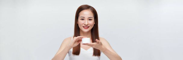 boldog fiatal ázsiai nő kezében üveg krém fehér transzparens - Fotó, kép