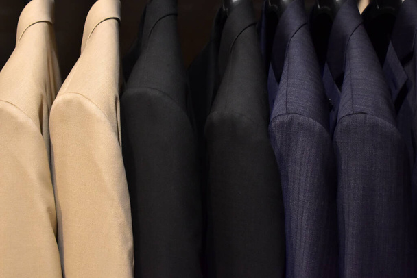 Suits on a clothing hanger. Merchandizing of clothes in a boutique. Clothing store fashion. - Photo, Image
