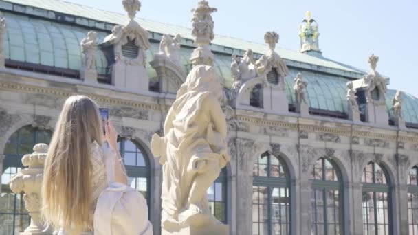 Fille touristique prenant des photos du palais de Zwinger, Dresde. Femme heureuse en vacances en Allemagne. Le concept des voyages touristiques en Europe. - Séquence, vidéo