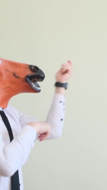 Crazy young man in a horse mask dancing rhythmically on a white background, slow motion. The holiday of happiness. Horse face. Positive emotions. Vertical video - Footage, Video