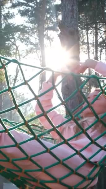 Eine junge Frau, die dem morgendlichen Sonnenaufgang begegnet, sitzt in einer Hängematte und streckt faul ihren Körper in die Höhe. Vertikales Video - Filmmaterial, Video
