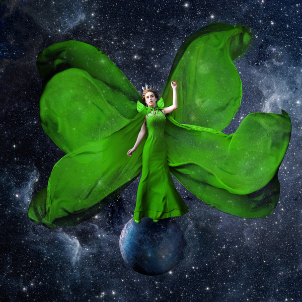 Green space queen. Beautiful woman in a fluttering dress standing and balancing on the planet in outer space. Fantastic art work. Elements of this image furnished by NASA. - Photo, Image