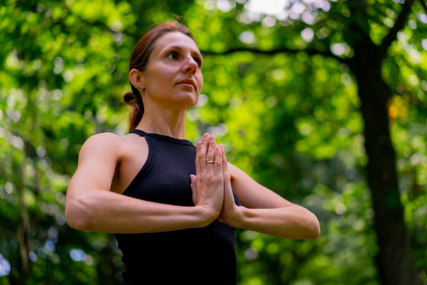 egy tapasztalt női oktató meditál a parkban gyakorlatok jóga nem nyújtás és gyakorlatok különböző izomcsoportok - Fotó, kép