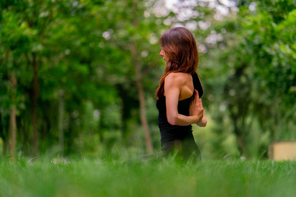 опытная женщина-инструктор медитирует в парке практики йоги делает растяжения и упражнения различных групп мышц - Фото, изображение