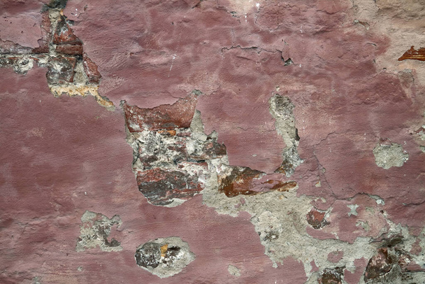 Uma parede de tijolo rosa com desmoronamento e gesso rachado - Foto, Imagem