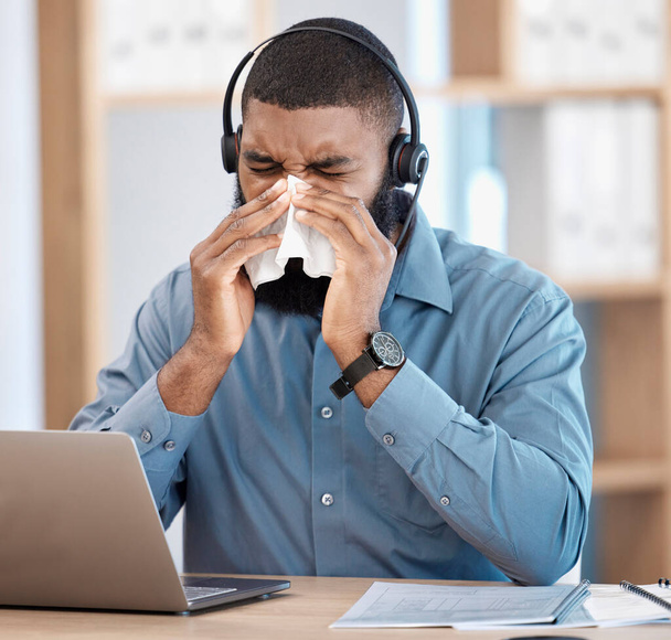 Czarny człowiek, chory i call center dmuchanie nosa z tkanek, alergii lub grypy w obsłudze klienta w biurze. Afrykański mężczyzna, konsultant lub agent z przeziębieniem, objawami lub wirusem immunologicznym w miejscu pracy. - Zdjęcie, obraz