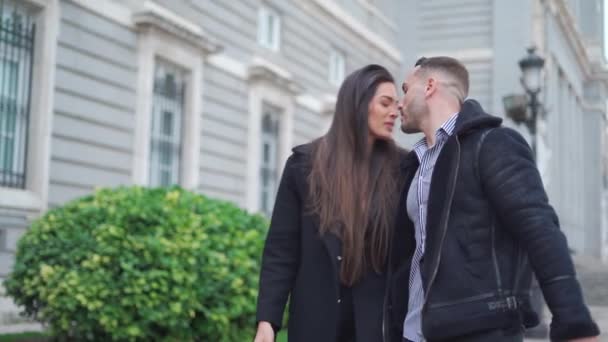 Αγαπώντας ευτυχισμένο ζευγάρι σε εξωτερικά ενδύματα κρατώντας τα χέρια, ενώ περπατάτε σε πλακόστρωτο διάδρομο στην πόλη - Πλάνα, βίντεο