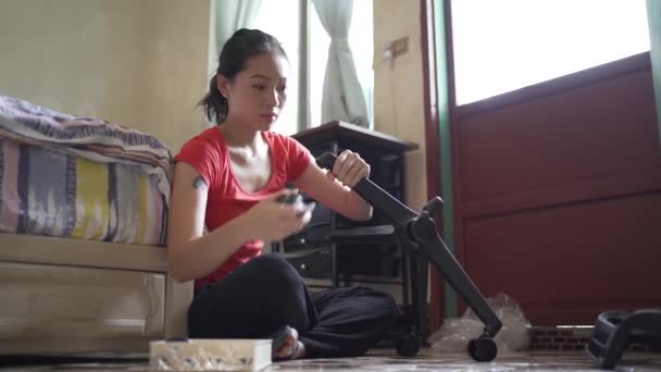 młody Azji kobieta naprawy krzesło w domu - Materiał filmowy, wideo