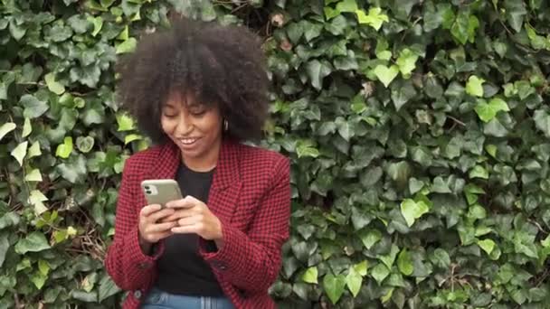 Contenu Afro-Américaine assise sur un banc en ville et bavardant de manière amusante - Séquence, vidéo