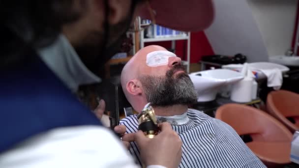 Middelbare leeftijd man wordt geschoren nauw door een geschoolde kapper - Video