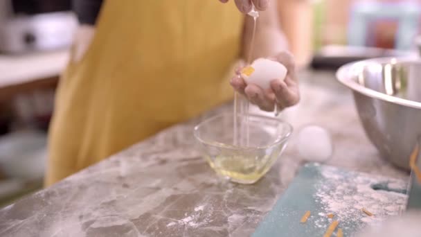 Кукурудза невпізнавана жінка середнього віку, що відокремлює сирий яєчний жовток від білого під час приготування їжі вдома - Кадри, відео