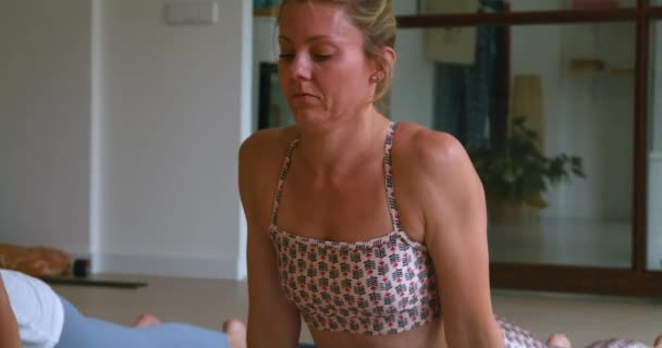 junge Sportlerinnen in aktiver Kleidung praktizieren morgens Yoga und führen verschiedene Stretching-Asanas im geräumigen Studio durch - Filmmaterial, Video