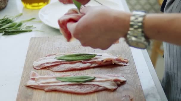 Temps réel de la récolte femelle anonyme mettant filet de veau non cuit avec prosciutto et sauge sur brochette en bois dans la cuisine - Séquence, vidéo