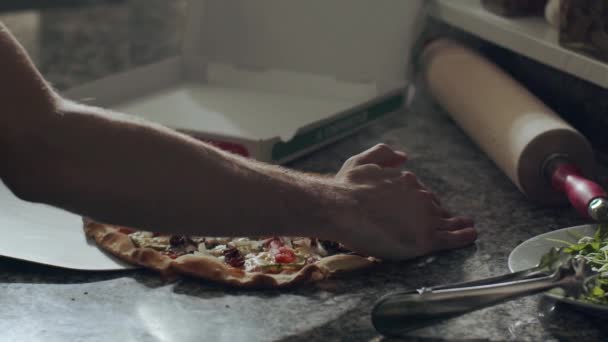 Καλλιεργείται αγνώριστο αρσενικό pizzaiolo με φτυάρι βάζοντας φρεσκοψημένα νόστιμα φέτες πίτσα σε χαρτοκιβώτιο για την παράδοση, ενώ εργάζονται στην πιτσαρία - Πλάνα, βίντεο