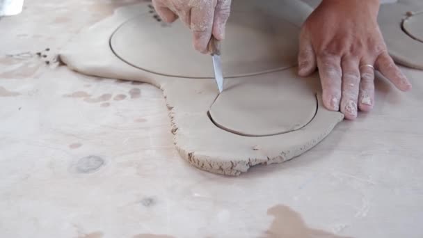 Recorte artista irreconocible con cuchillo cortar círculos de arcilla mientras se trabaja en el taller - Metraje, vídeo