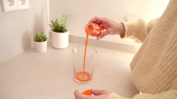 nő öntés friss gyümölcslé üvegbe a konyhában - Felvétel, videó