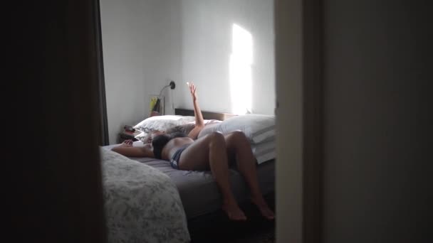 Tranquillo afroamericano femminile sdraiato su un letto morbido e facendo ombre sulla parete con mano - Filmati, video