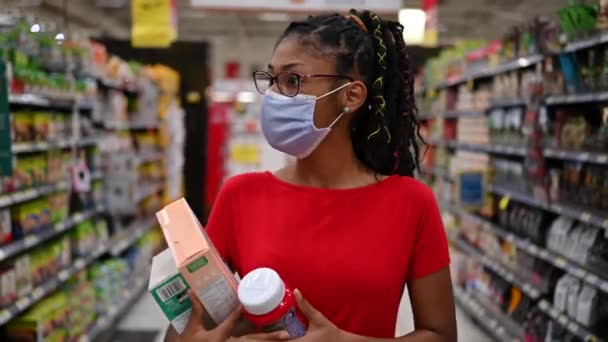 Afro latina joven mujer usando un rostro máscara compras conforman productos - Metraje, vídeo