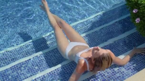 Από πάνω του ευτυχισμένη λεπτή γυναίκα ταξιδιώτη σε μαγιό που βρίσκεται στην πισίνα και ηλιοθεραπεία με κλειστά μάτια - Πλάνα, βίντεο