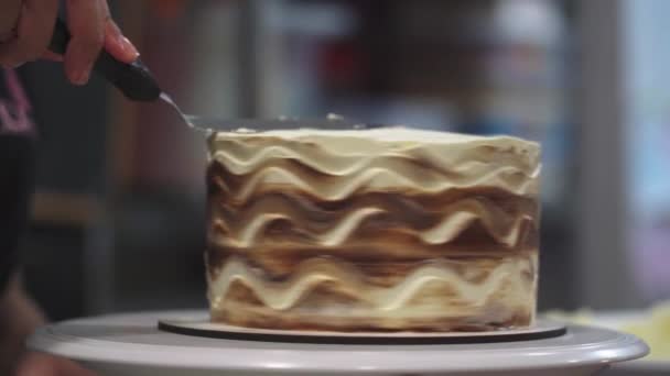 Reálný čas plodin nepoznatelný profesionální cukrář vyrovnávání sladký pečený dort s polevou na stojanu v kuchyni na rozmazaném pozadí - Záběry, video