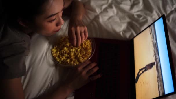 Asiática hembra acostada en una cama mientras ve una película en un ordenador portátil en casa. - Metraje, vídeo
